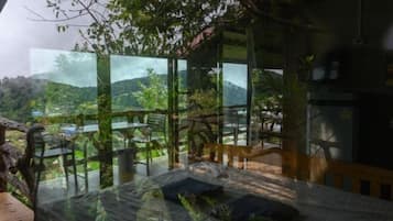 Una habitación moderna con pared de vidrio, cama y vista a un paisaje montañoso.
