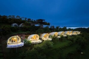 A series of dome-shaped accommodations with a central open area, surrounded by greenery and overlooking a body of water. - Mon View Ngam (Mae Rim)