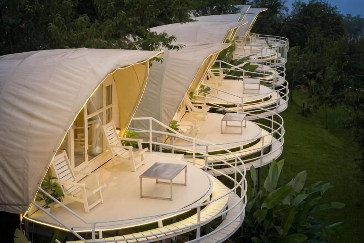 A series of connected, tent-like structures with outdoor seating and a central table.