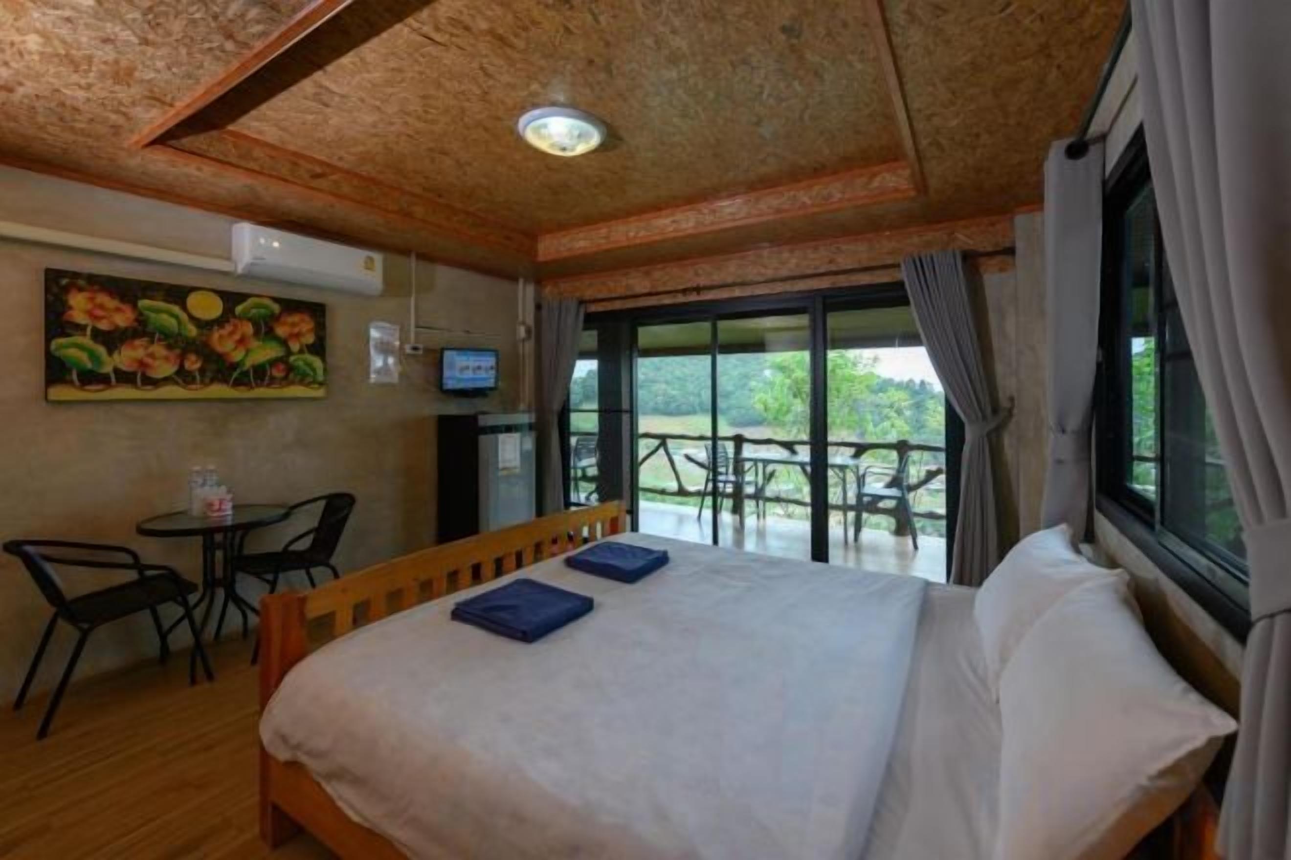 A bedroom with a bed, a television, a table, and chairs.