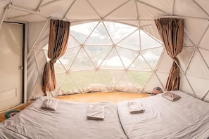 A dome-shaped tent with a bed, curtains, and a view of the outdoors. - Mon View Ngam (Mae Rim)