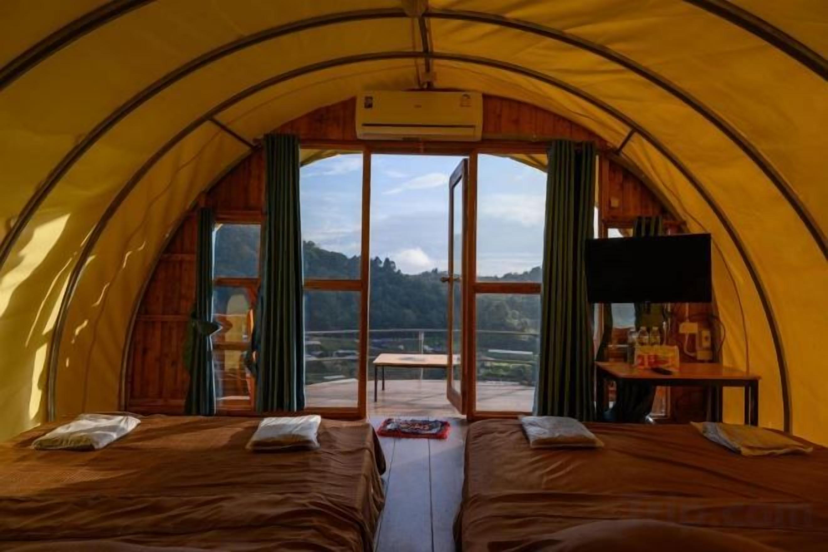 A tent with two beds, a table, and a TV.
