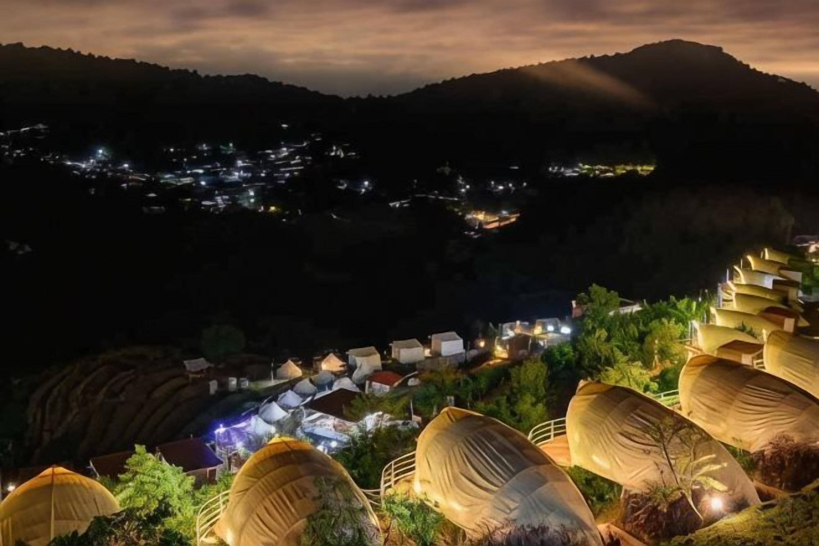 Ein Dorf mit terrassenförmig angelegten Feldern und Häusern in der Nacht.
