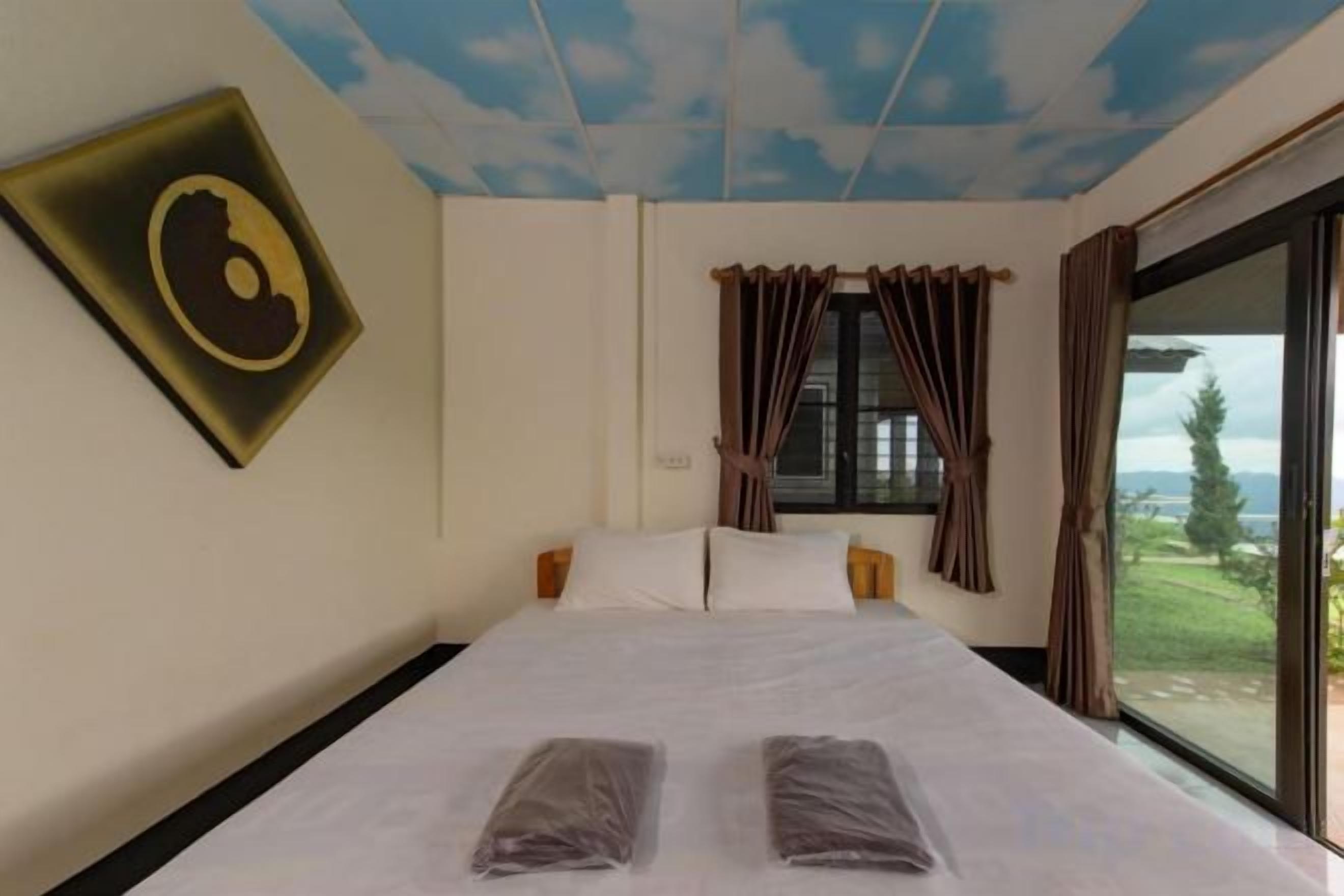 A hotel room with a bed, curtains, a window, and a view of the outdoors.
