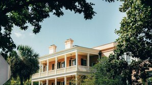 A two-story building with a balcony, surrounded by greenery. - Savannah Serendipity | Historic Broughton St (Savannah)
