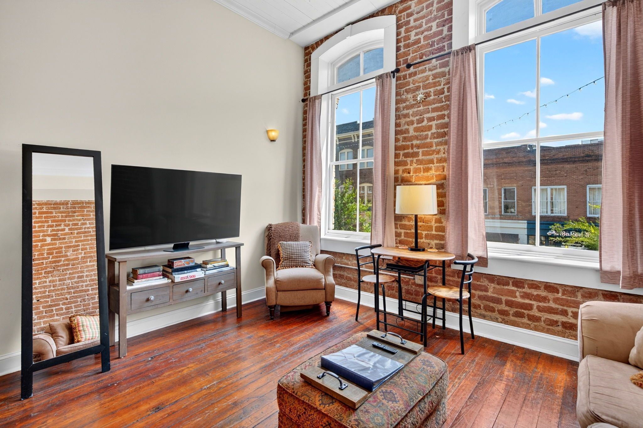 A living room with a television, books, a chair, a table, and a lamp.