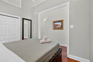 A bedroom with a bed, a wall-mounted painting, and a door.