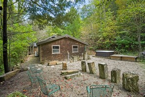 A rustic cabin with a gravel patio, surrounded by trees.
