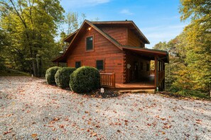 A wooden cabin with a porch, surrounded by trees and gravel. - Oasis Glen - Views, Pool, Hot Tub (Rockbridge)