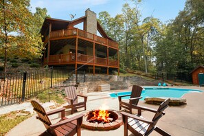 A cabin with a deck, a fire pit, and a pool.