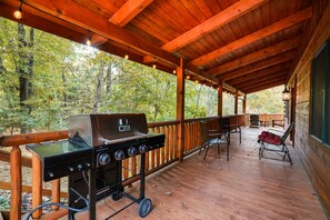 A covered outdoor deck with a grill, chairs, and a view of a forest. - Oasis Glen - Views, Pool, Hot Tub (Rockbridge)