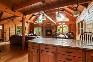 L’intérieur d’une cabane en rondins, avec une cheminée, des meubles en bois et un mur en pierre.