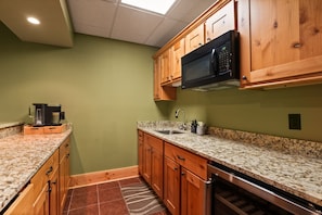 A kitchen with wooden cabinets, granite countertops, a microwave, and a coffee maker.
