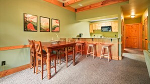 A dining area with a wooden table and chairs, a kitchen with wooden cabinets, and a ceiling fan.