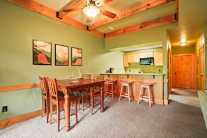 A dining area with a wooden table and chairs, a kitchen with wooden cabinets, and a ceiling fan.