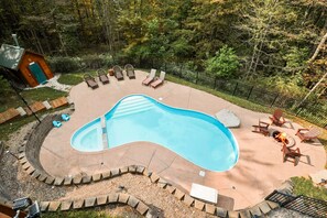 Une piscine avec un foyer et des chaises longues.