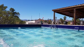 A swimming pool with a tiled edge, a covered area with a roof, and a building in the background. - Posada de las Flores Loreto (Loreto)