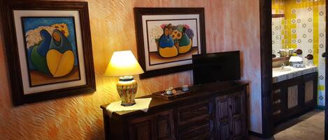 A room with a wooden cabinet, a television, and two framed artworks on the wall.