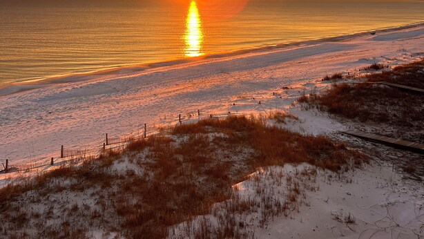 A beach with a sunset, sandy dunes, and a wooden fence. - Gulf Front 3 Bedroom Condo in Mexico Beach at The Vue (Mexico Beach)