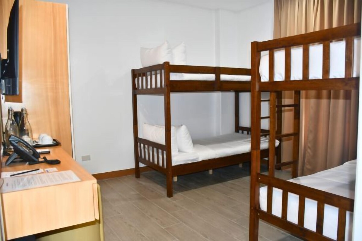 A room with two wooden bunk beds, a desk with a telephone, and a chair.