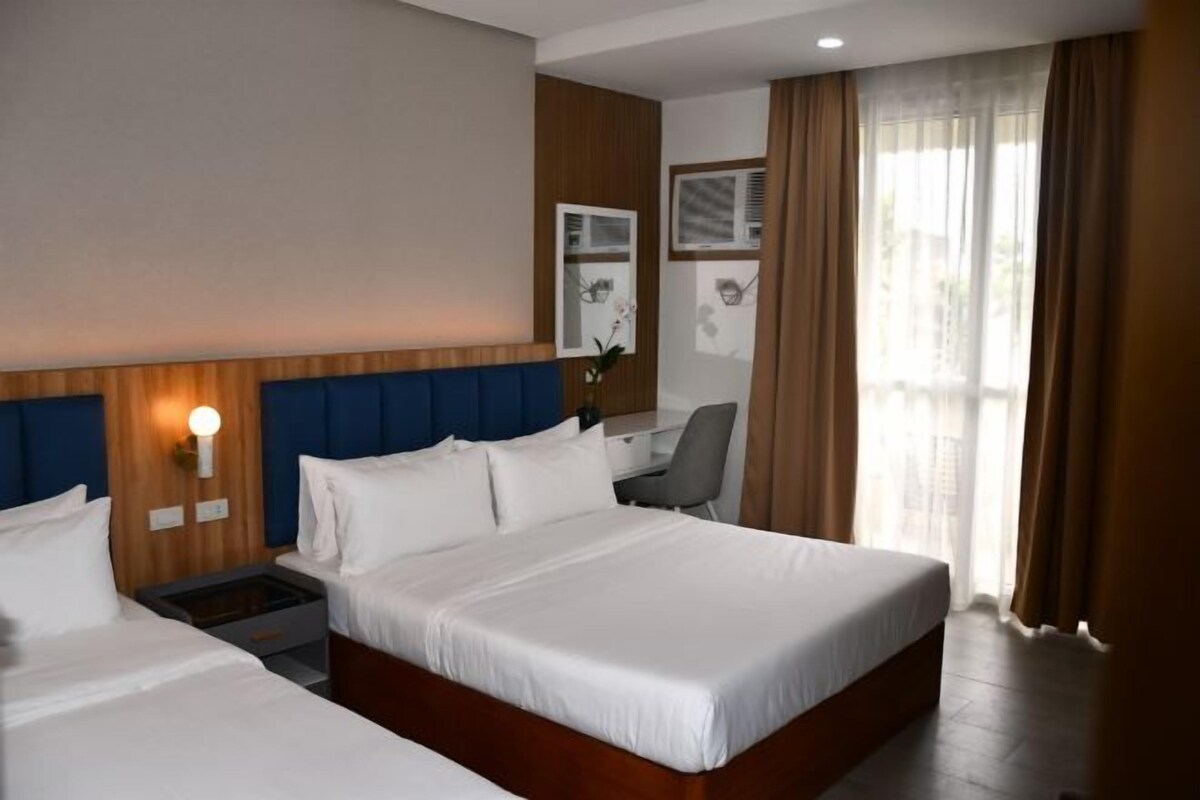 A hotel room with a large bed, a desk, and a chair.