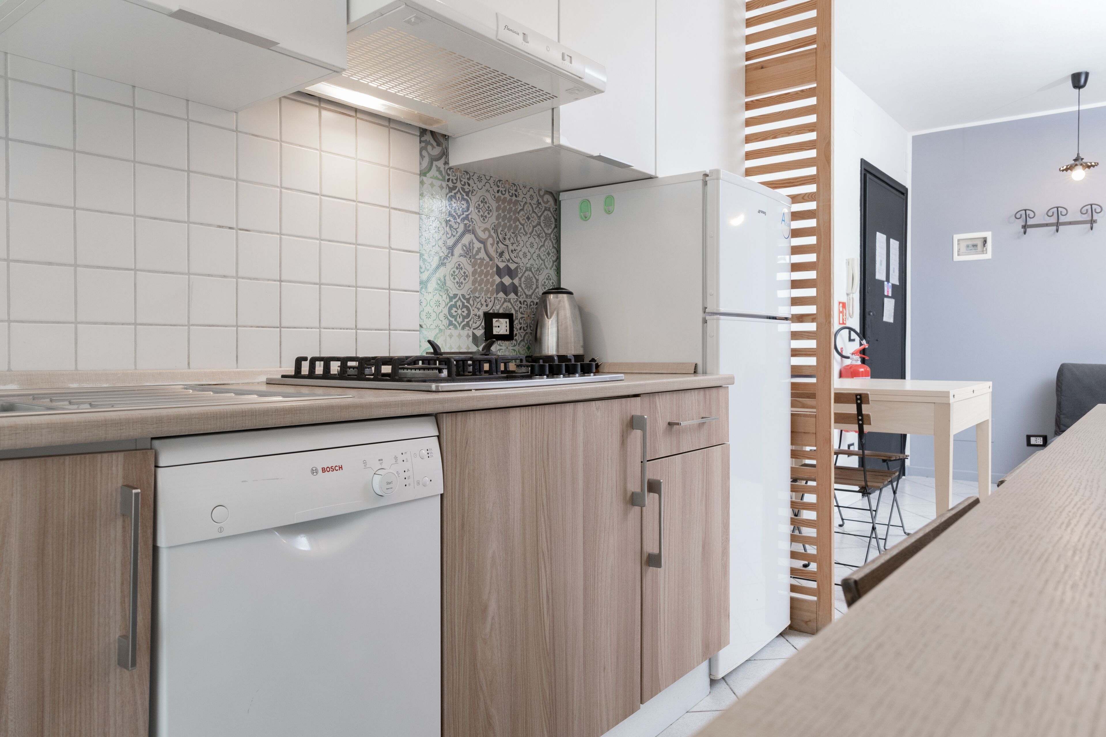 A modern kitchen with a Bosch dishwasher, a stove, and a refrigerator.