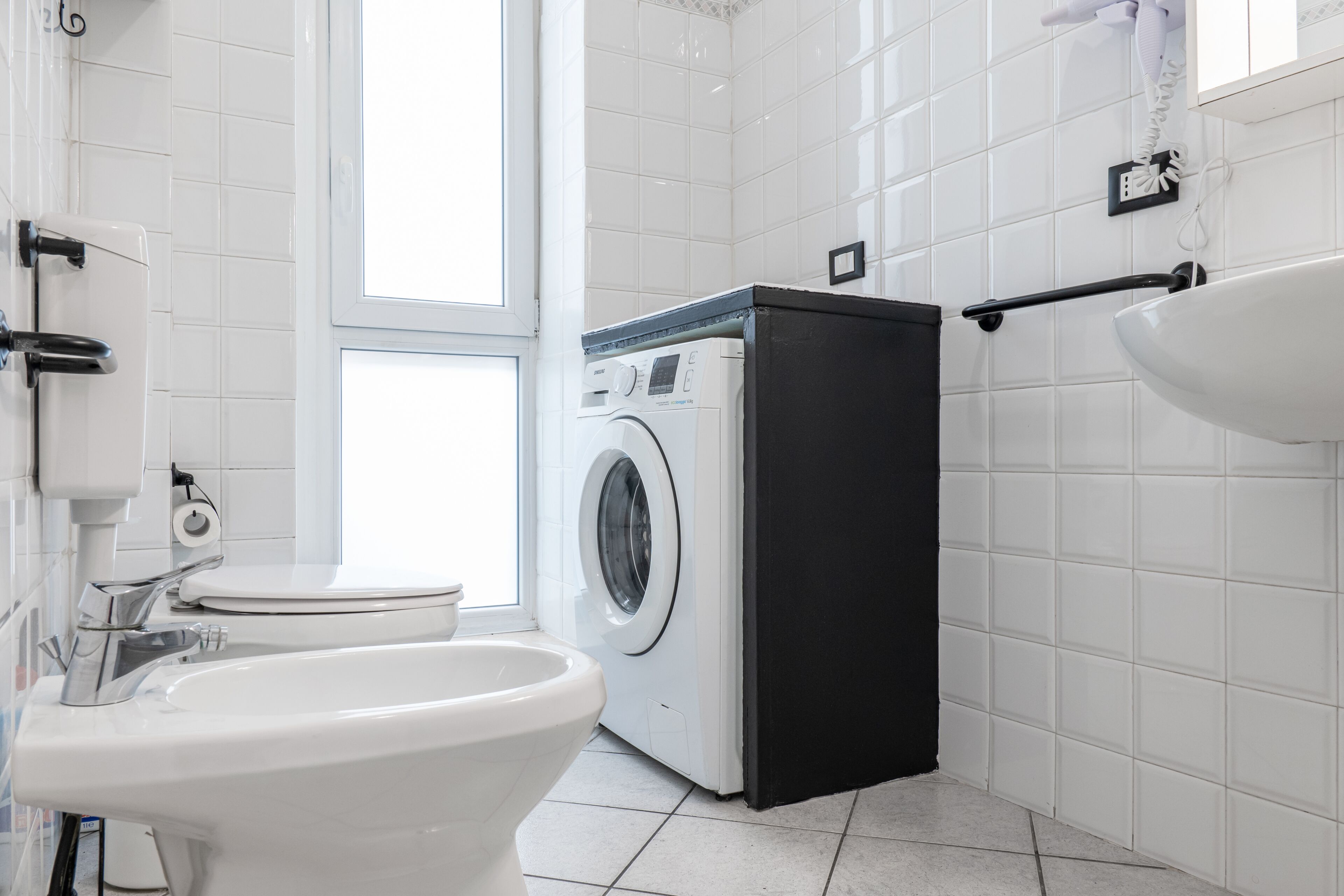 A modern bathroom with a toilet, washing machine, and sink.