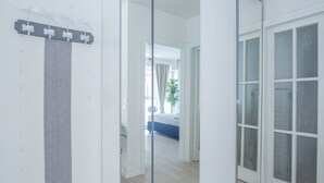 Une chambre d’hôtel moderne avec un grand miroir, un rideau à rayures grises et une vue sur la chambre voisine.