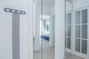 Camera d'albergo moderna con un grande specchio, una tenda a righe grigie e vista sull'stanza confinante.