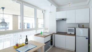Une cuisine moderne avec des armoires blanches, un plan de travail en bois, un four encastré, un four à micro-ondes et un réfrigérateur.