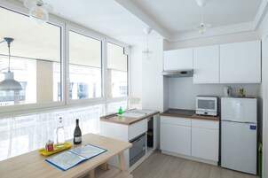 Una cucina moderna con mobili bianchi, un piano di lavoro in legno, forno integrato, microonde e frigorifero.