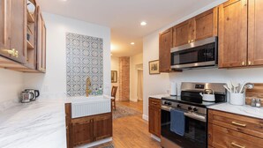 A kitchen with wooden cabinets, a microwave, a stove, and a sink. - Downtown Luxury Apartment I Full Kitchen I W/D (Moscow)