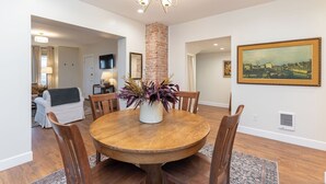 A dining area with a round wooden table, chairs, a potted plant, a brick column, and a painting on the wall. - Downtown Luxury Apartment I Full Kitchen I W/D (Moscow)