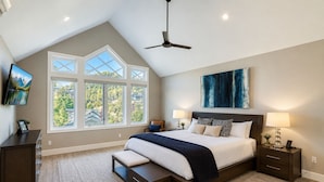 A bedroom with a large bed, a ceiling fan, a TV, and a view of the outdoors. - Old Town Park City Luxury with Private Spa and Views 440 (Park City)