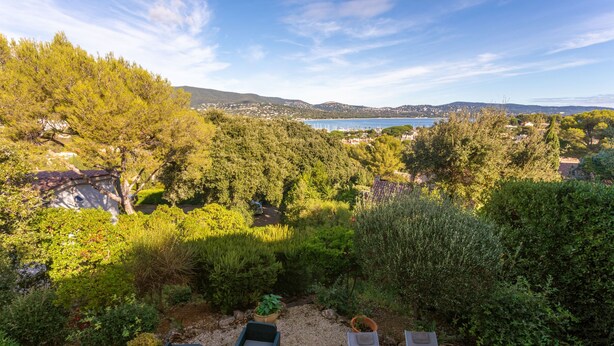 A garden with outdoor seating and a view of a lake and distant buildings. - Villa 'La Mignonette' with Sea View, Private Garden and Wi-Fi (Cavalaire-sur-Mer)