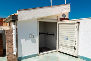 A small, enclosed outdoor area with a white door and a clock on the wall.