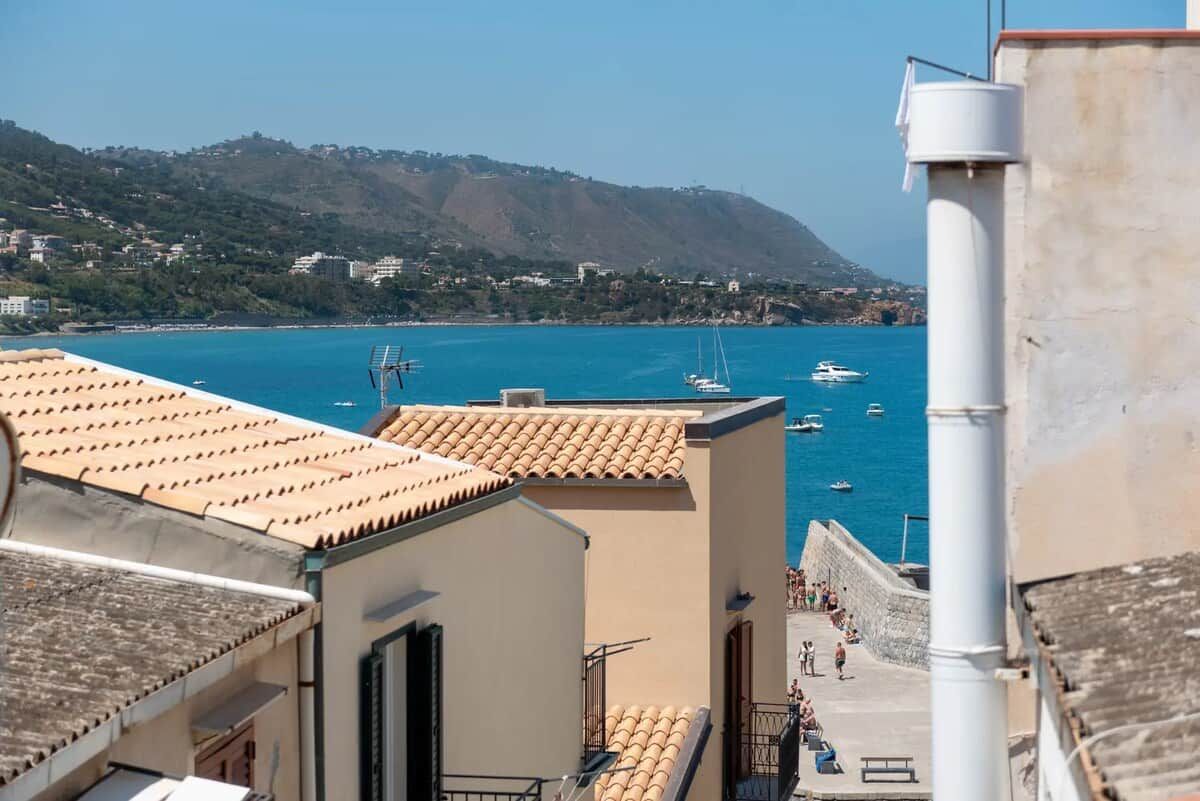 Une vue sur la côte, avec des bâtiments, un ciel dégagé et des bateaux sur l’eau.