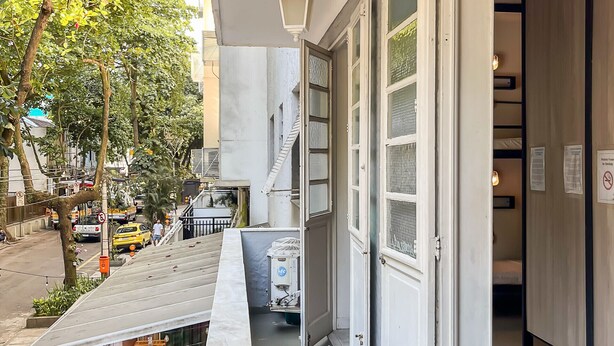 A hotel corridor with a wooden bench seating area, a staircase, and a door leading to a room. - Hostel Leblon - 12-bed mixed shared room (Rio de Janeiro)