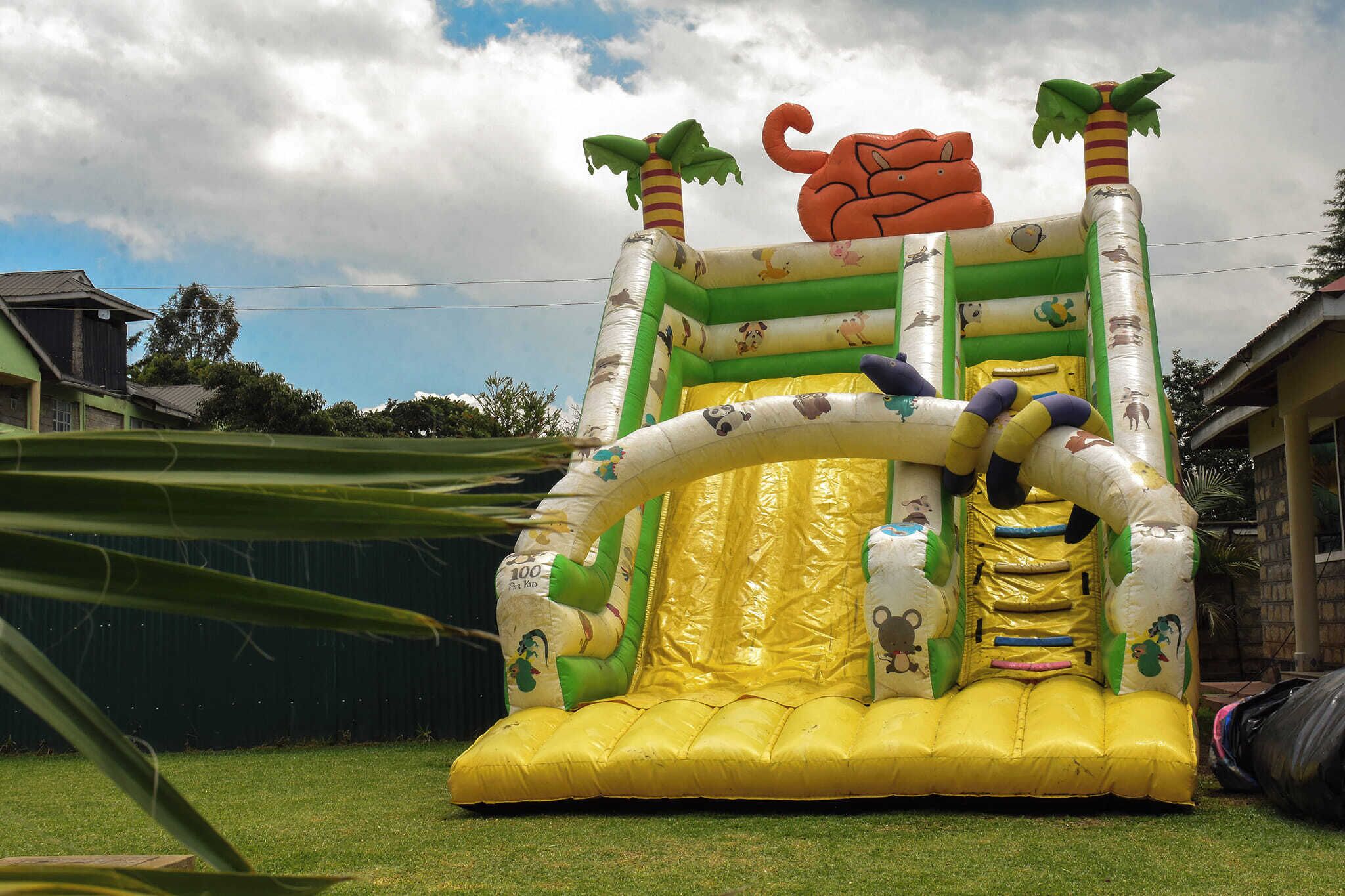 A large inflatable play structure with slides and climbing areas, set in a grassy yard.