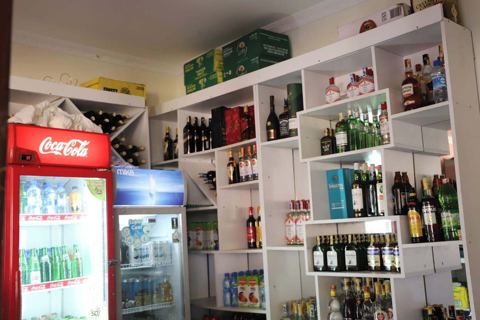 Un espace de stockage pour les boissons, équipé d’étagères remplies de diverses boissons, notamment des bouteilles et des canettes.
