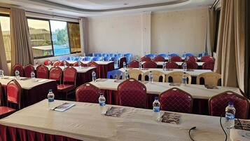 Un salón de conferencias con mesas, sillas, botellas de agua y tarjetas de identificación.