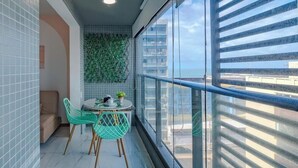 A balcony with a dining table, chairs, and a view of the city.