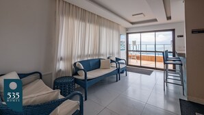 A modern hotel room with a balcony, wicker furniture, and a view of the sea.
