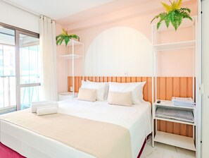Ein Hotelzimmer mit einem großen Bett, einem hölzernen Kopfteil, einem weißen Regal mit einer Pflanze und Blick auf die Stadt durch das Fenster.