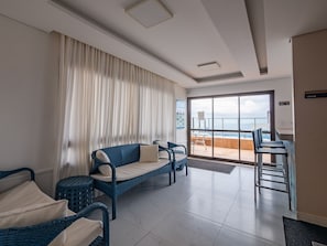 Ein modernes Hotelzimmer mit Balkon, Korbmöbeln und Meerblick.