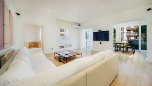 Ein modernes Wohnzimmer mit einer Couch, einem Couchtisch und einem an der Wand befestigten Fernseher.