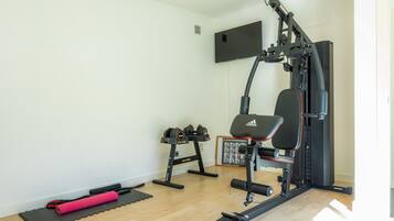 Ein Heim-Fitnessraum mit einer Langhantelbank, Kurzhanteln und einer Klimmzugstange.