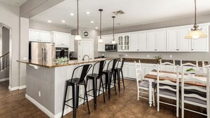 A modern kitchen with white cabinets, a granite countertop, and a central island with bar stools.