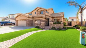 A two-story house with a stone facade, a garage, and a well-maintained lawn.