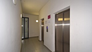 Un pasillo con una puerta, un ascensor y un cartel en la pared.